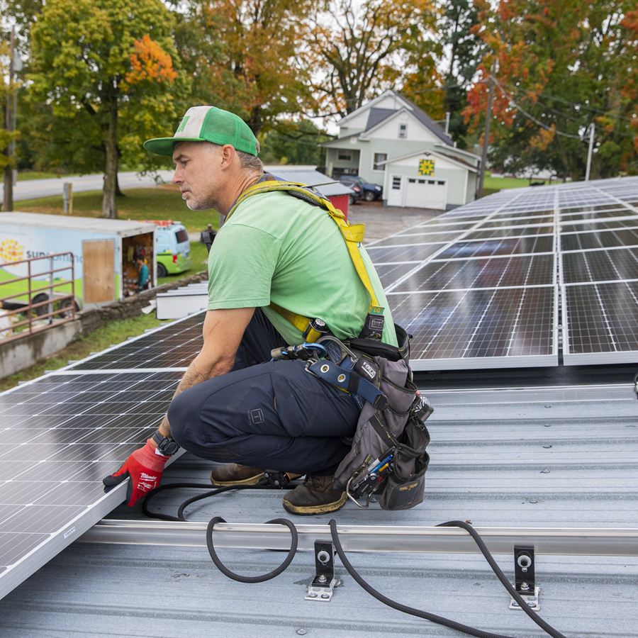 Senior technician working on a standing-seam metal roof solar installation