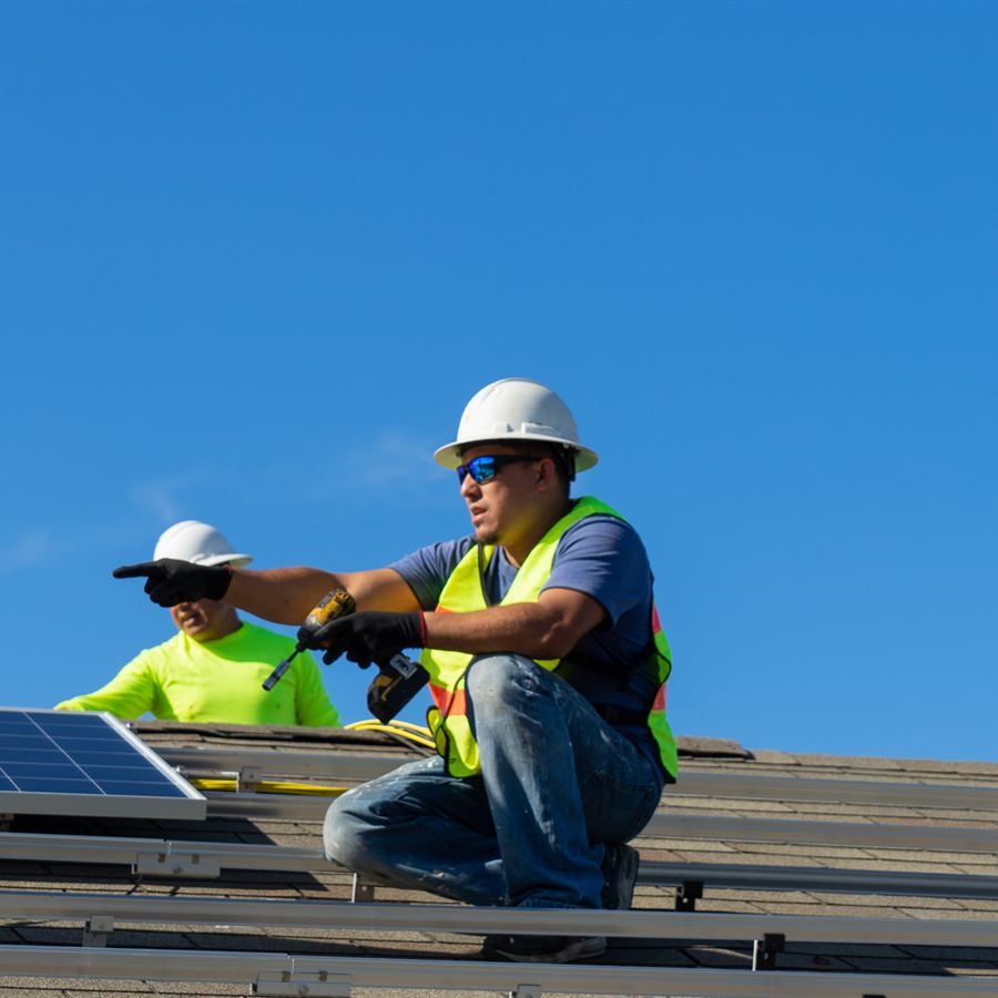 Technicians installing solar modules on a rooftop